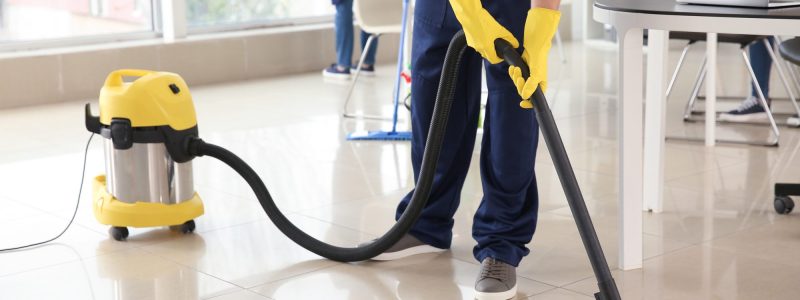 Janitor hoovering floor in office