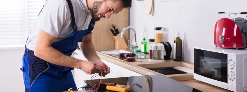 Technician Repairing Induction Stove In Kitchen